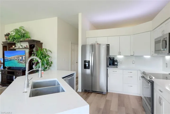Kitchen with light hardwood / wood-style flooring, stainless steel appliances, backsplash, sink, and white cabinetry
