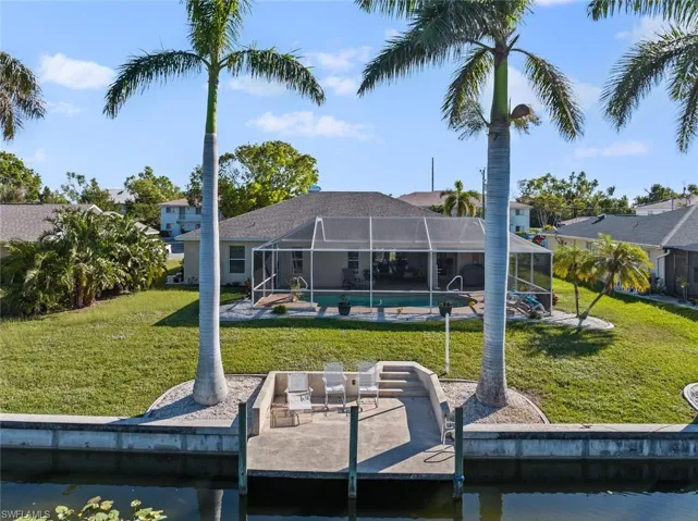 Dock area with a lawn, glass enclosure, and a water view