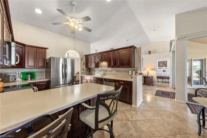 Kitchen featuring tasteful backsplash, ceiling fan, lofted ceiling, and appliances with stainless steel finishes