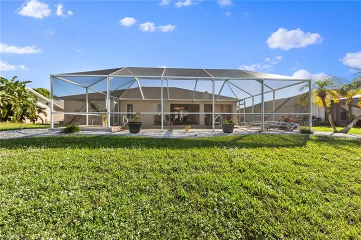 Back of house featuring a lawn and glass enclosure