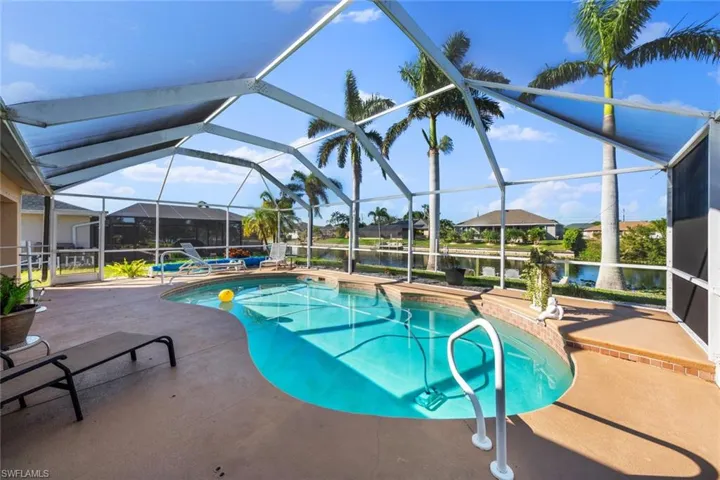 View of swimming pool with a patio, a water view, and a lanai