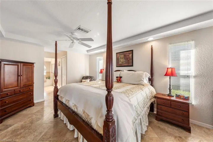 Bedroom featuring ceiling fan, a textured ceiling, and ensuite bath