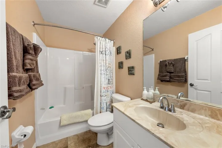 Full bathroom featuring vanity, toilet, shower / bath combo with shower curtain, and a textured ceiling