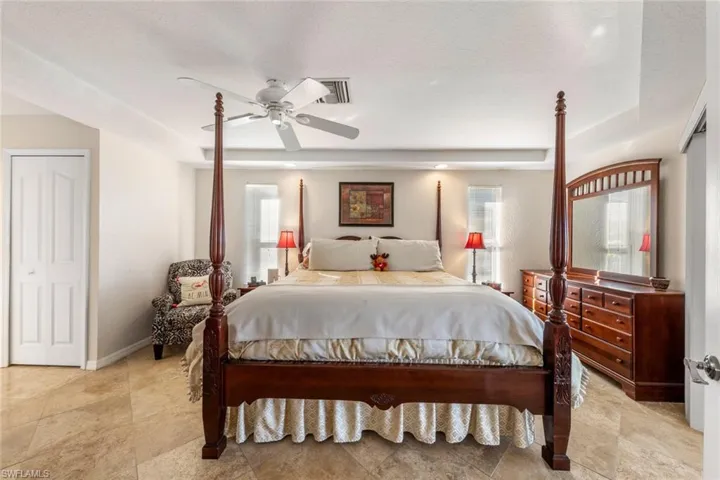 Bedroom featuring multiple windows, a textured ceiling, a tray ceiling, and ceiling fan