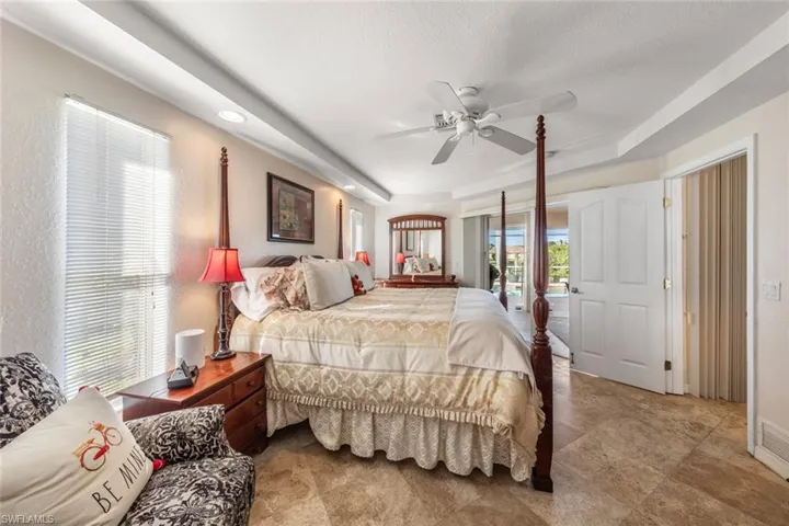 Bedroom featuring a textured ceiling, access to outside, a raised ceiling, and ceiling fan