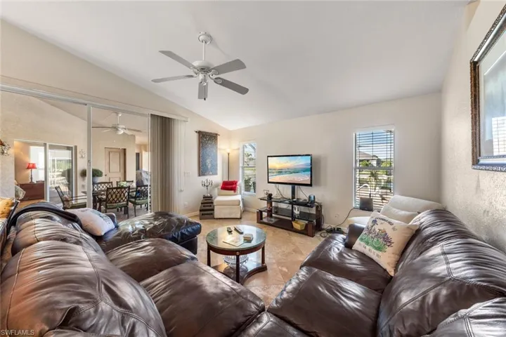 Living room featuring vaulted ceiling, ceiling fan, and light tile patterned flooring