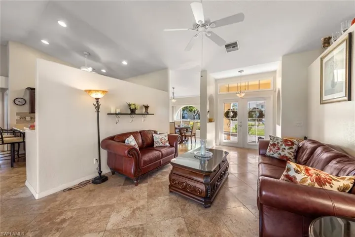 Living room with ceiling fan, lofted ceiling, and french doors