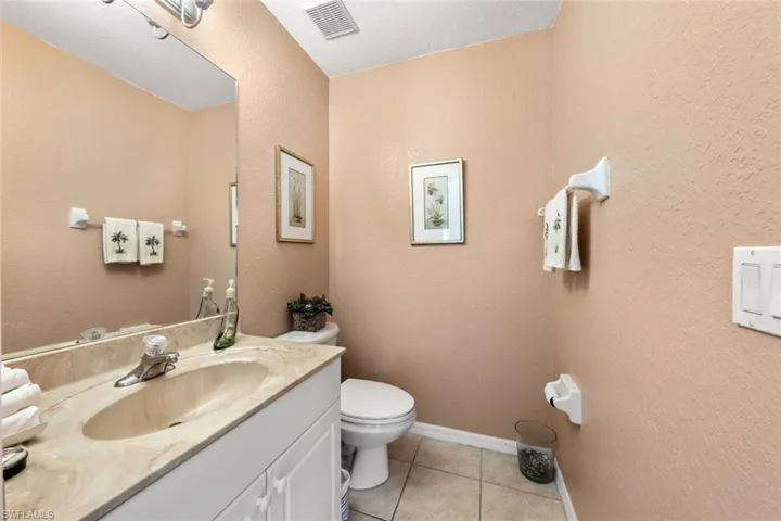 Bathroom with tile patterned flooring, vanity, toilet, and a textured ceiling