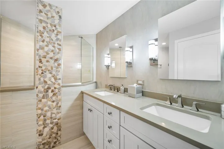Bathroom with tile walls, a tile shower, vanity, and water heater