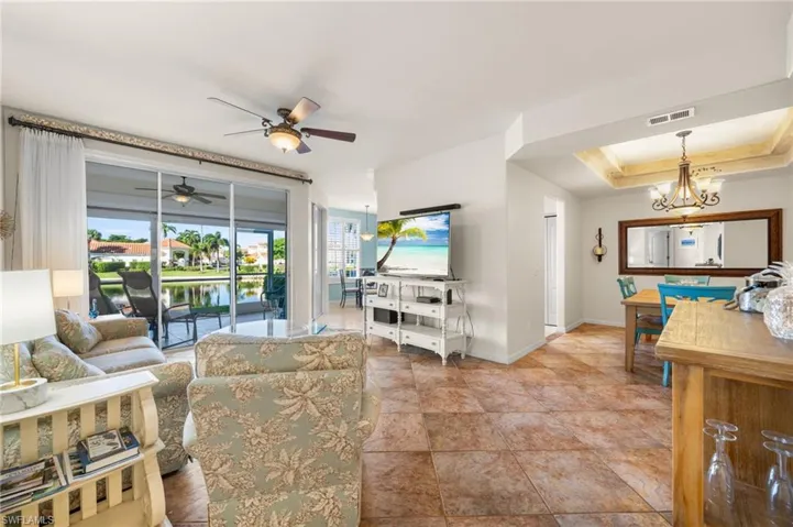 Living room featuring ceiling fan with notable chandelier and a raised ceiling