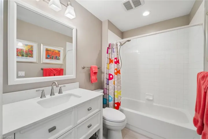The single vanity has a quartz countertop and a shower / tub combo.