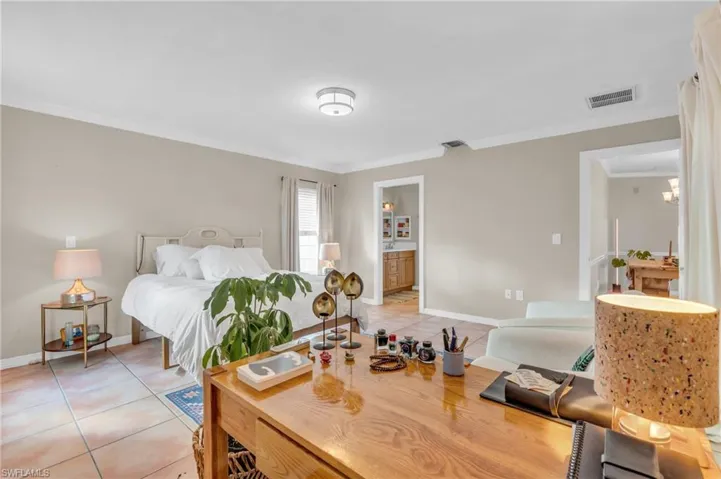 Bedroom with ensuite bath, crown molding, and light tile patterned flooring
