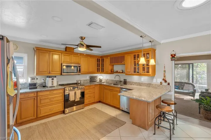 Kitchen with a wealth of natural light, kitchen peninsula, a breakfast bar, and appliances with stainless steel finishes