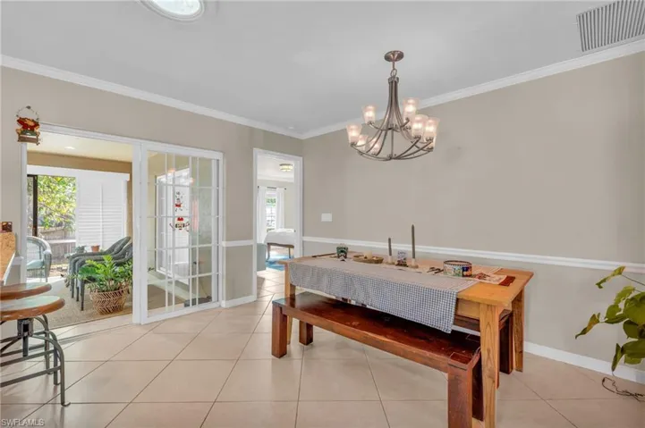 Tiled dining room with crown molding and a chandelier