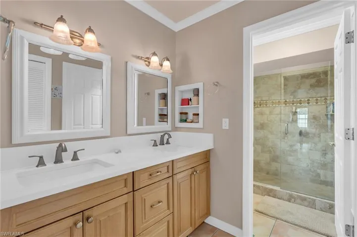 Bathroom with tile patterned floors, crown molding, vanity, and a shower with shower door
