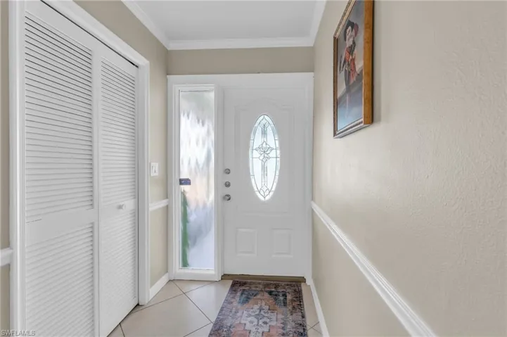Entryway with light tile patterned flooring and ornamental molding