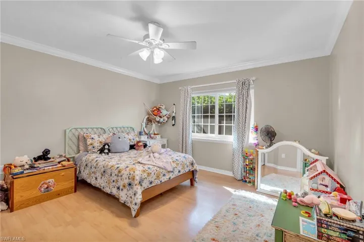 Bedroom featuring hardwood / wood-style flooring, ceiling fan, and ornamental molding