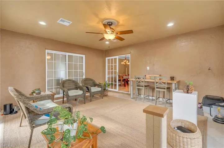 Living room featuring tile patterned floors and ceiling fan with notable chandelier