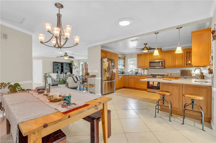 Tiled dining area featuring sink, ceiling fan with notable chandelier, and ornamental molding