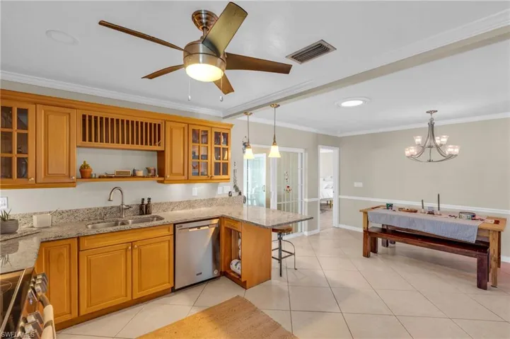 Kitchen with pendant lighting, sink, ornamental molding, appliances with stainless steel finishes, and light stone counters