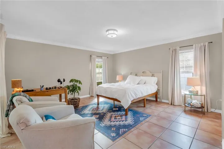 Bedroom with multiple windows, crown molding, and light tile patterned floors