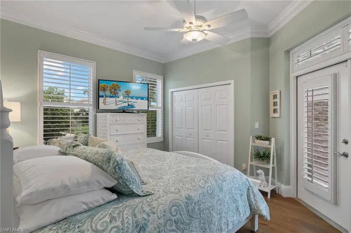 Bedroom featuring dark wood-type flooring, a closet, ceiling fan, and crown molding