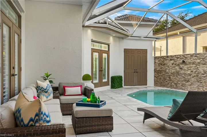 View of pool featuring outdoor lounge area, glass enclosure, a patio, and french doors