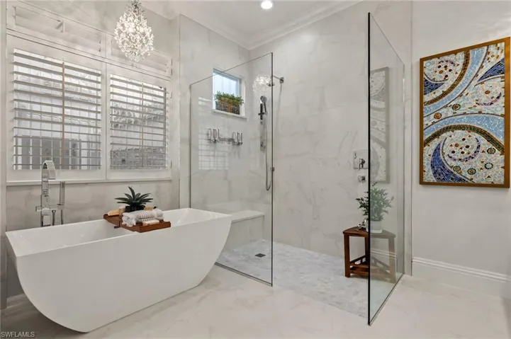 Bathroom with shower with separate bathtub, a notable chandelier, and ornamental molding