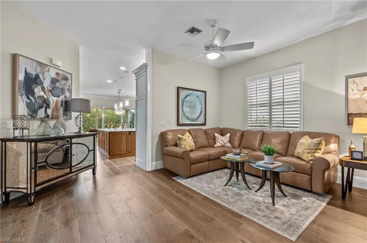 Living room with ceiling fan with notable chandelier and dark hardwood / wood-style flooring
