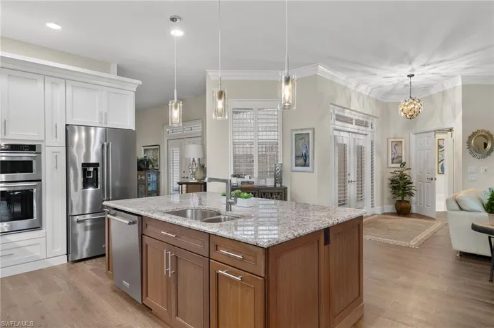 Kitchen with a center island with sink, stainless steel appliances, sink, white cabinetry, and light wood-type flooring