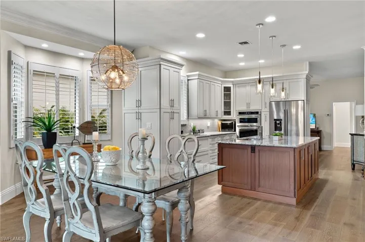 Kitchen featuring light stone countertops, a center island with sink, appliances with stainless steel finishes, light hardwood / wood-style floors, and hanging light fixtures