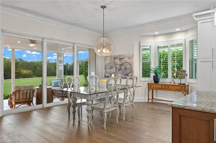 Dining room with light wood-type flooring, ornamental molding, and ceiling fan with notable chandelier