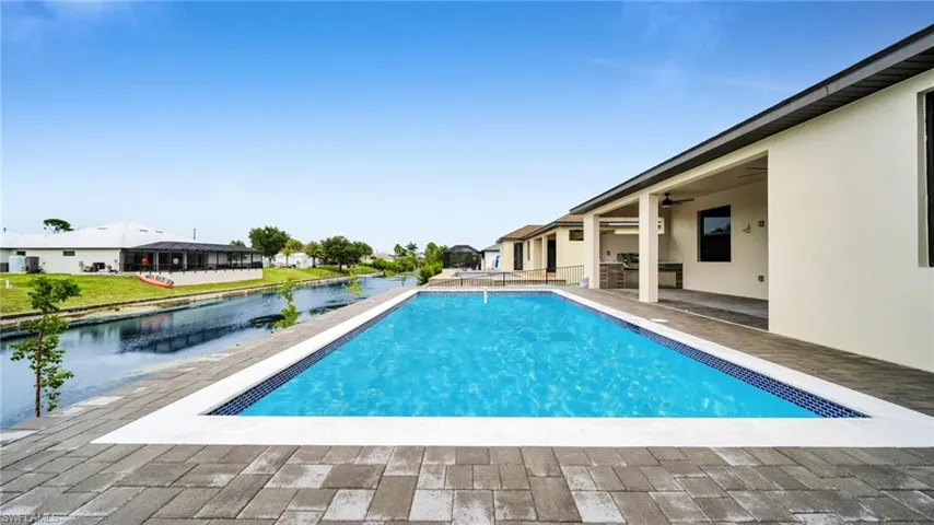 Swimming pool with a patio area, area for grilling, a residential view, and a water view