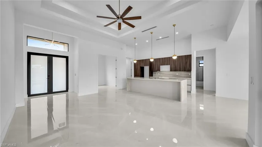 Kitchen with a high ceiling, modern cabinets, a large island, light stone counters, and open floor plan