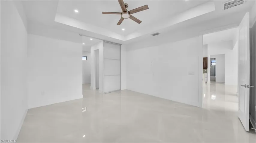 Unfurnished bedroom with a tray ceiling, recessed lighting, and ceiling fan