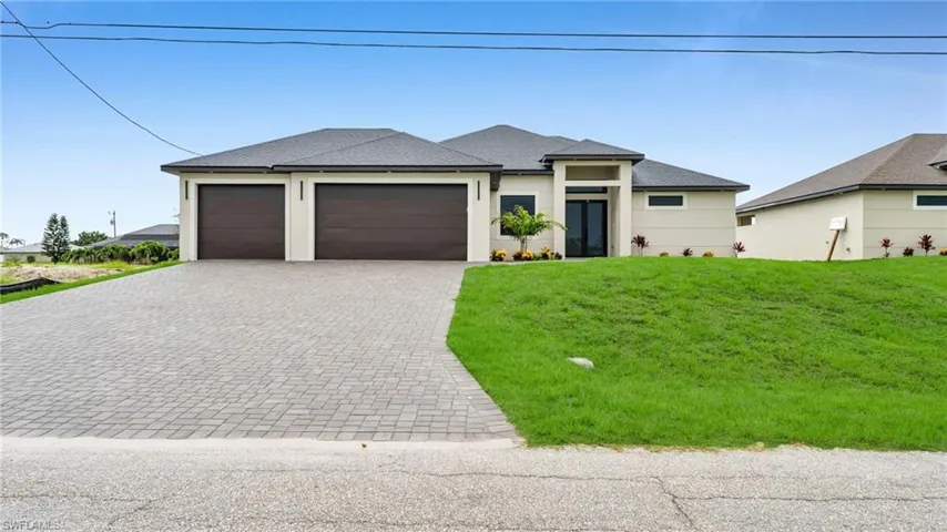 Prairie-style home featuring a front yard, decorative driveway, a garage, a shingled roof, and stucco siding