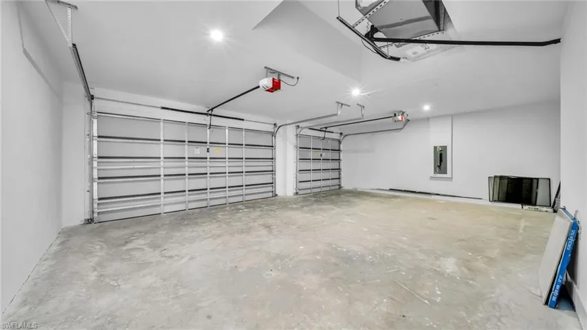 Garage featuring electric panel, recessed lighting, and a garage door opener