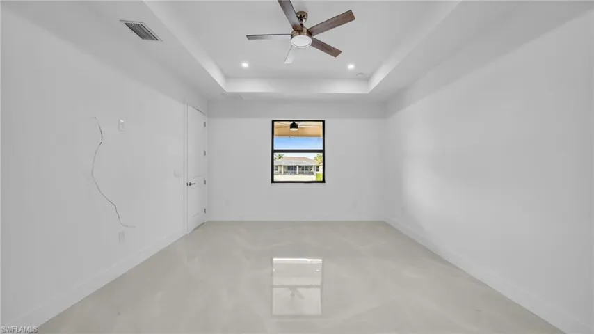 Spare room with ceiling fan, a raised ceiling, and recessed lighting