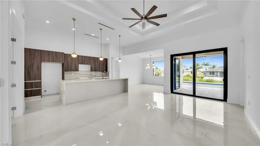 Unfurnished living room featuring hanging lights, ceiling fan, and a high ceiling