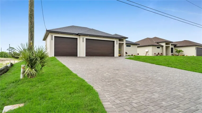 Prairie-style house featuring a front lawn, driveway, stucco siding, an attached garage, and roof with shingles