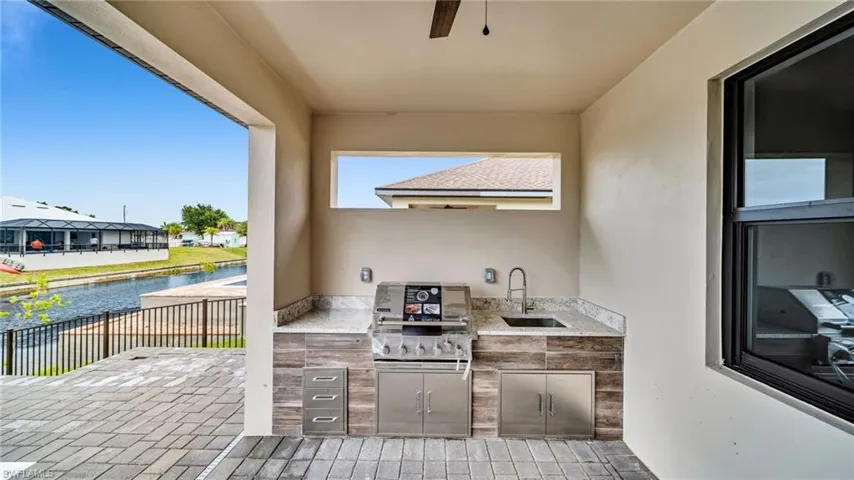 View of patio / terrace with exterior kitchen, a ceiling fan, a water view, and a residential view