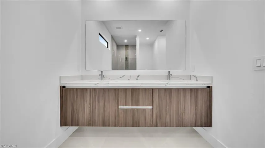 Full bath featuring double vanity, a stall shower, light tile patterned floors, and recessed lighting