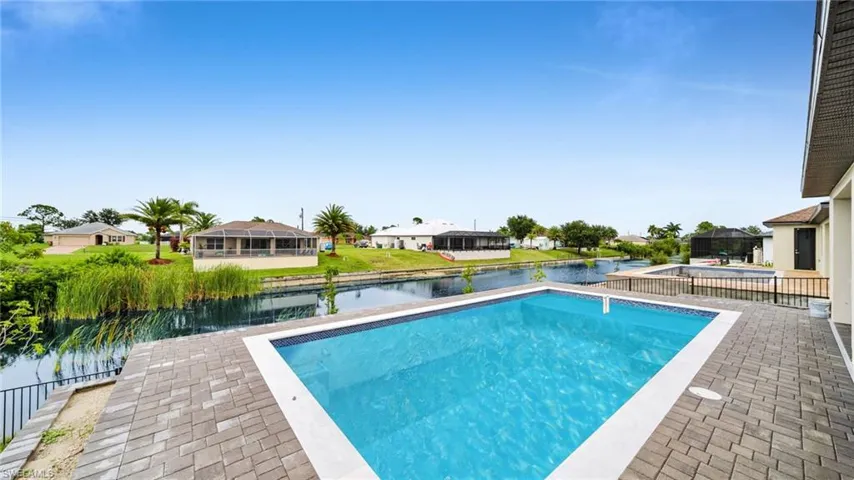 Outdoor pool with a patio area, a water view, and a residential view