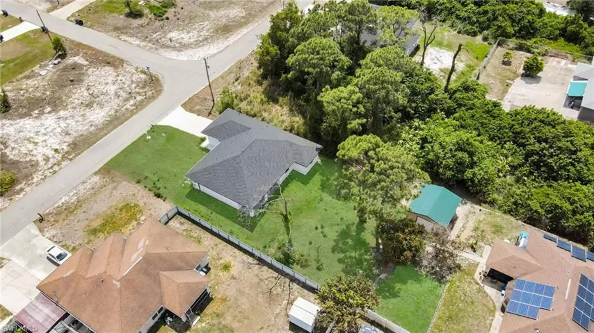 New construction residence featuring a dark shingle roof, a verdant lawn, and a light-colored exterior