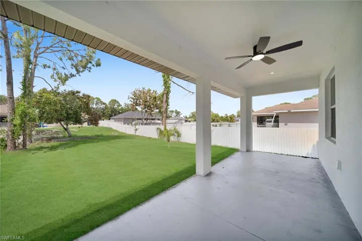 Spacious covered patio with a contemporary ceiling fan, concrete flooring, and multiple support columns