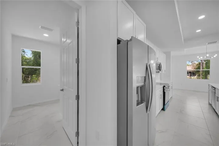 Open-concept kitchen featuring stainless steel appliances, white cabinetry, recessed lighting, and tile flooring
