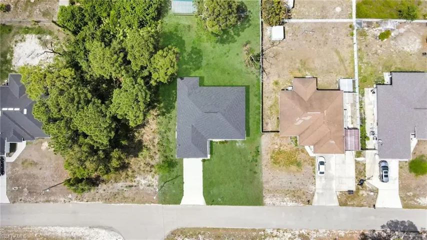 Aerial perspective showcasing a property with a dark shingle roof and a concrete driveway