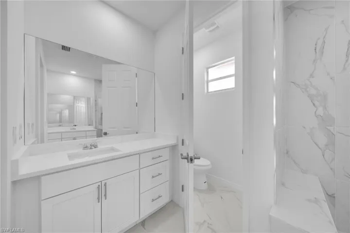 Bathroom featuring a white vanity with an undermount sink, a quartz-finish countertop, and ample storage cabinetry