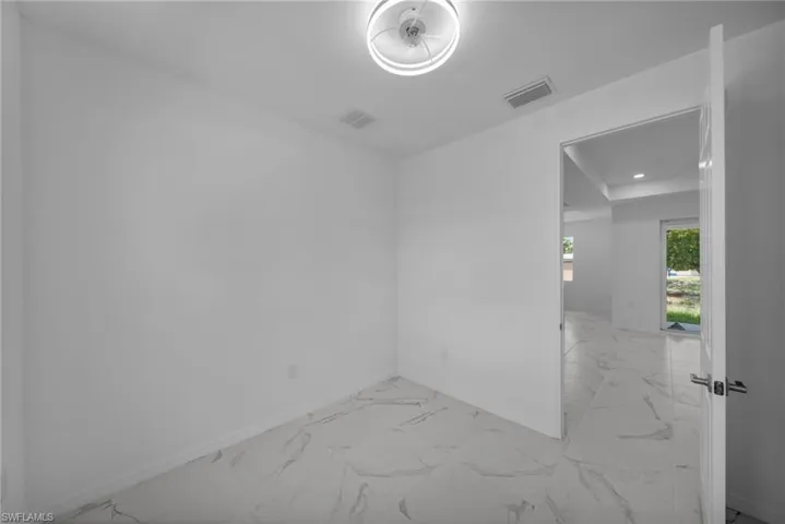 DEN !Bright white room featuring large format tile flooring with subtle veining, a modern flush-mount ceiling light, and white baseboards