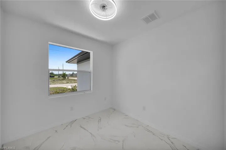 DEN! Room featuring a white-framed window, white walls, and large format marble-look tile flooring